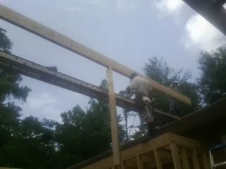 Carpenter setting a ridge beam over a new addition frame — Ice Dam Removal by Roofing Brothers in Becker