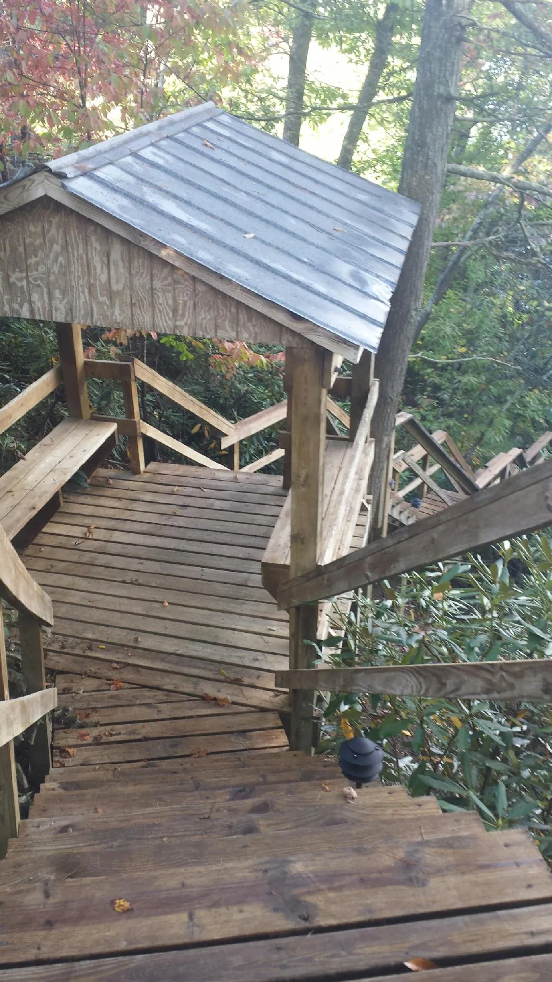Metal roofed shelter over wooden steps on a wooded walkway — Skylight Repair & Installation work by our crew in Becker