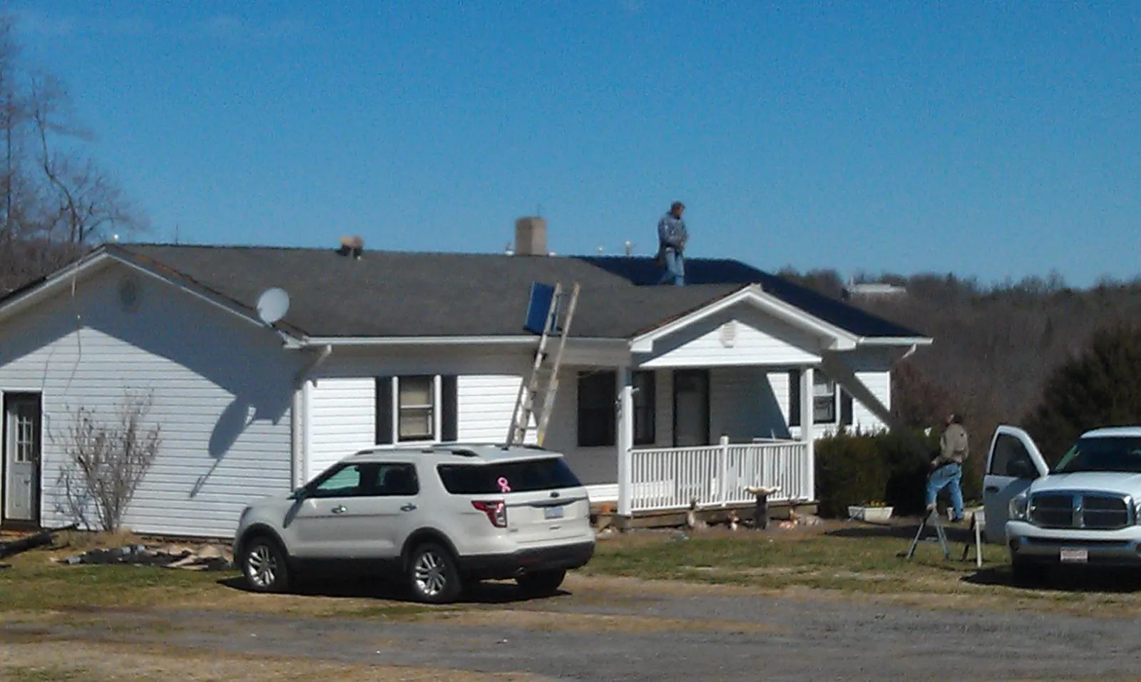 Roofers stripping shingles from a white ranch house roof in Becker