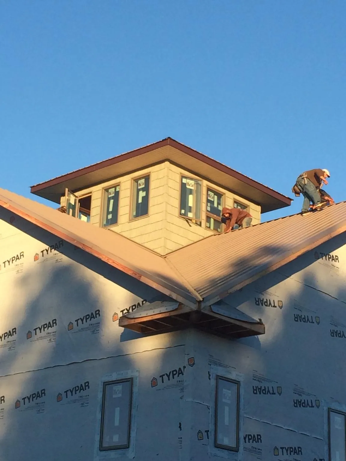 Roofers working around a rooftop cupola on a new metal roof at sunset — Roof Waterproofing in Becker by Roofing Brothers